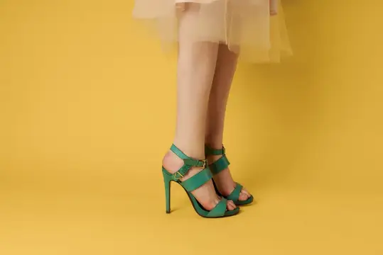 Женские ступни в зелёной обуви, элегантный стиль, модная обувь на жёлтом фоне