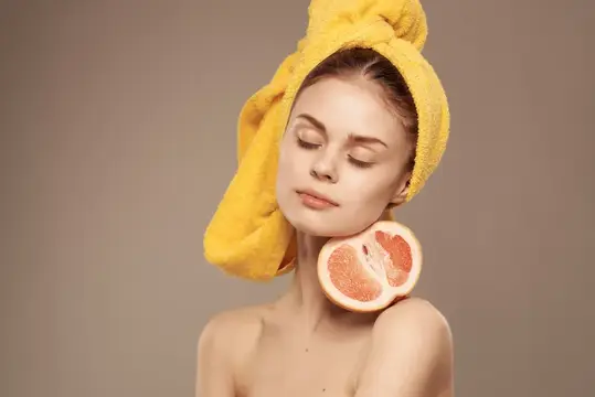 Красивая женщина с обнажённым телом после душа, держащая в руке грейпфрут, кадрированный вид