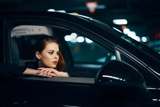 Рыжеволосая девушка смотрит в окно автомобиля ночью