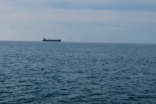 Открытая вода и далекое судно на безмятежном горизонте над бескрайним морем, подчеркивающие морское спокойствие, широкий морской пейзаж и одинокое плавание в море