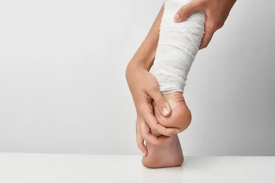 Руки накладывают эластичный бинт на голеностоп