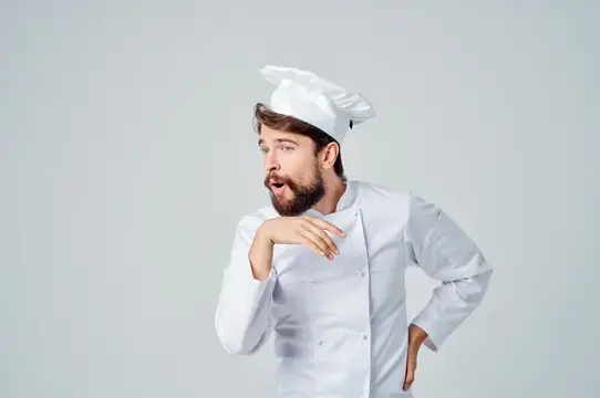 Удивлённый бородатый повар в белом колпаке и кителе