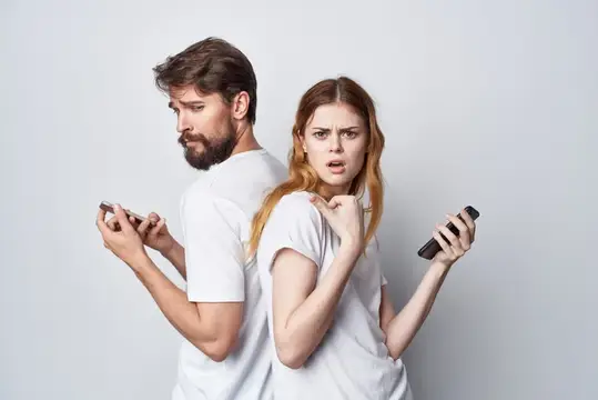 Мужчина и женщина стоят спиной к спине со смартфонами
