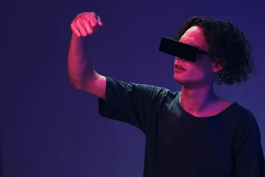 Кудрявый парень в VR-очках поднимает кулак в неоновом свете