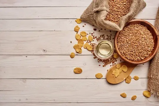 Зерна пшеницы в мешке и миске на светлом деревянном столе