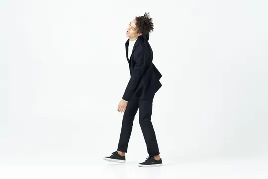 Симпатичный парень с кудрявыми волосами в черном костюме разливает напиток на светлом фоне