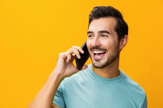 Улыбающийся бородатый мужчина говорит по телефону на жёлтом фоне