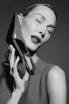 Девушка с закрытыми глазами держит туфлю на каблуке у лица