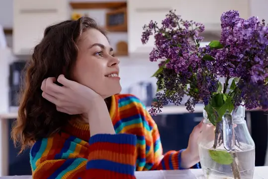 Улыбающаяся девушка с букетом сирени на кухне