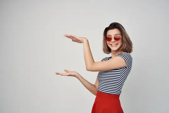 Улыбающаяся девушка в красных очках показывает руками большой размер
