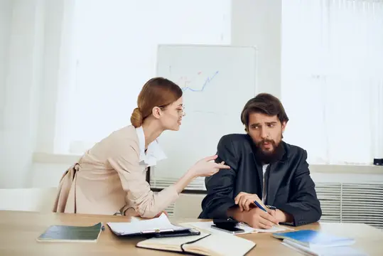 Женщина с указкой объясняет график бородатому коллеге в офисе