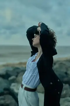 Молодая женщина с закрытыми глазами на ветру у моря