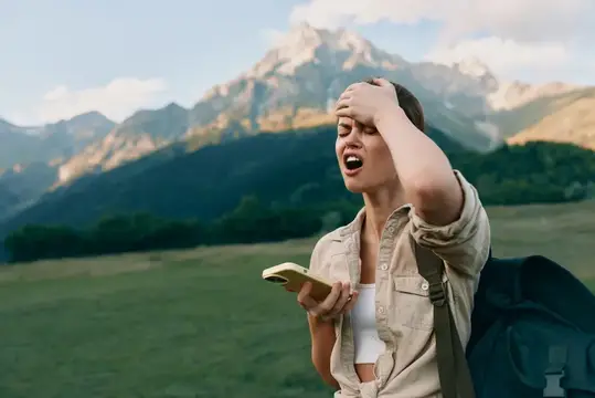Уставшая туристка с блокнотом на фоне горных вершин