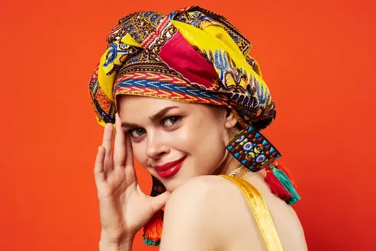 Улыбающаяся светловолосая девушка в ярком тюрбане на оранжевом фоне