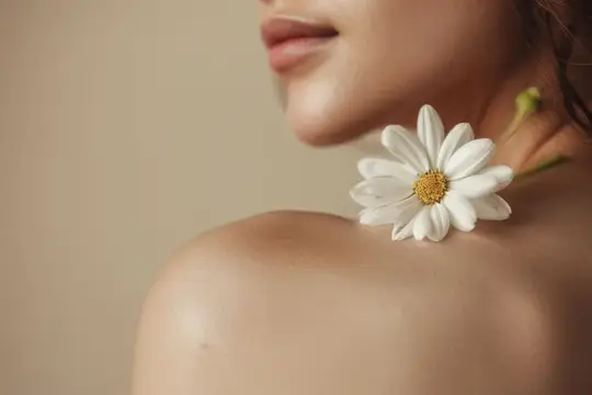 Белая хризантема лежит на плече девушки