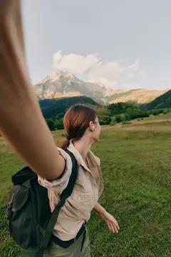 Девушка с рюкзаком делает селфи на фоне гор