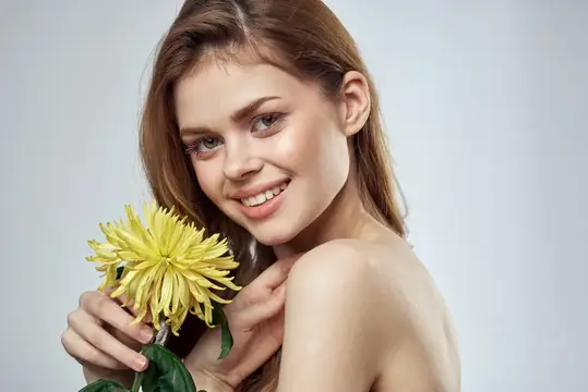 Улыбающаяся светловолосая девушка с жёлтым цветком в руках