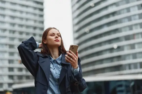 Молодая женщина с телефоном на фоне высотных зданий