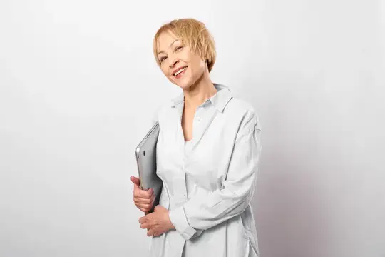 Улыбающаяся блондинка в белой рубашке держит ноутбук
