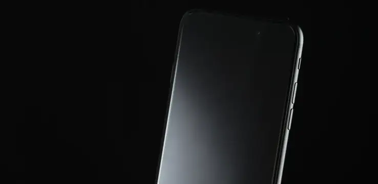 Черный смартфон с выключенным экраном на темном фоне