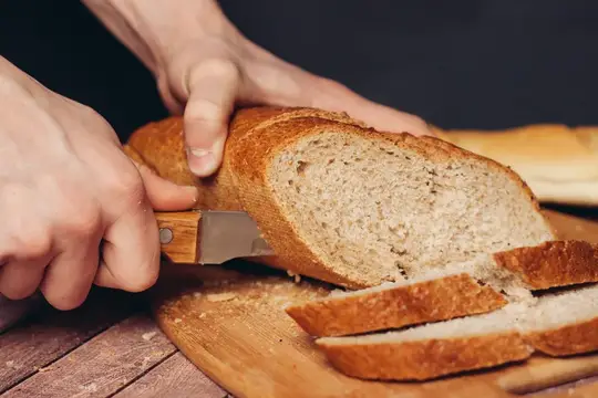 Нарезанная свежая буханка хлеба на деревянной разделочной доске, кухня и еда