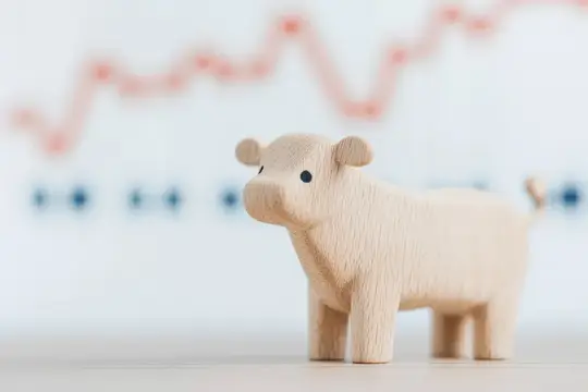Деревянная фигурка свиньи на фоне размытого графика роста
