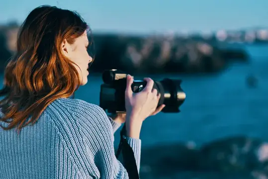 Женщина на открытом воздухе с профессиональной камерой на фоне скалистых гор и свежего воздуха