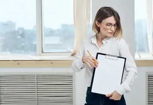 Молодая женщина в очках с планшетом у окна в офисе