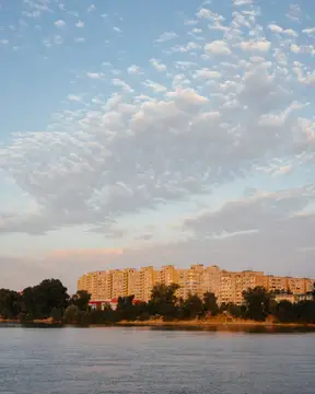 Панорама города с многоэтажками у реки на закате