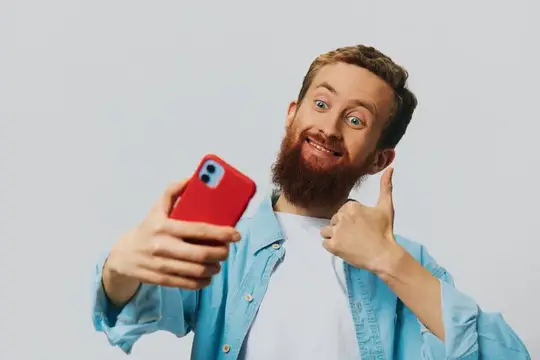 Бородатый мужчина с красным смартфоном показывает большой палец вверх