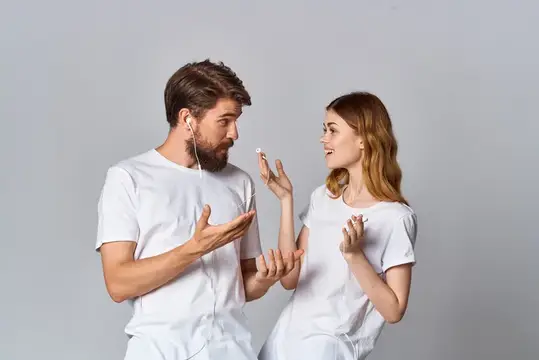 Молодые мужчина и женщина в белых футболках слушают музыку в наушниках