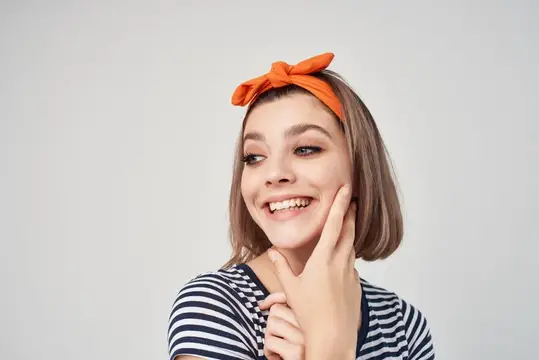 Улыбающаяся девушка с оранжевым бантом на голове
