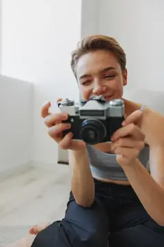 Улыбающаяся девушка с пленочным фотоаппаратом в руках