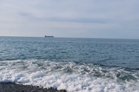Одинокий грузовой корабль на горизонте спокойного моря