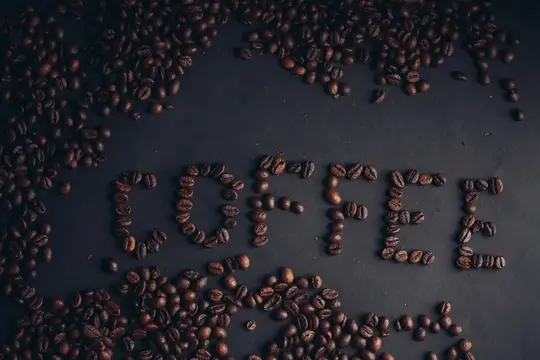 Кофейные зерна, выложенные словом coffee на темном фоне