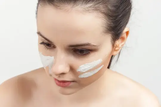 Брюнетка с кремовой маской для лица, обнаженные плечи, улыбка