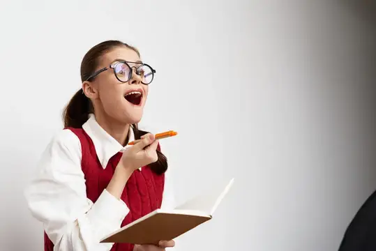 Улыбающаяся девушка в очках держит блокнот и выглядит взволнованной