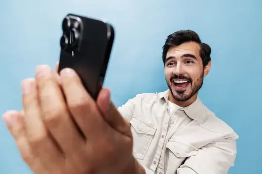 Улыбающийся бородатый мужчина делает селфи на смартфон