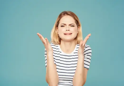 Расстроенная женщина на синем фоне жестикулирует руками