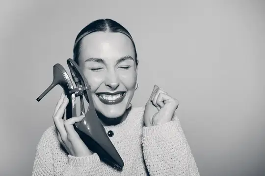 Улыбающаяся женщина с туфлями на каблуках у лица