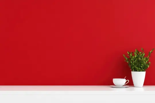Яркая сцена с ярко-красной стеной, дополненной белой полкой, на которой стоит комнатное растение и чашка с блюдцем