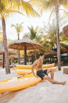 Счастливый азиатский мужчина, занимающийся водными видами спорта на тропическом пляже: приключение на байдарке