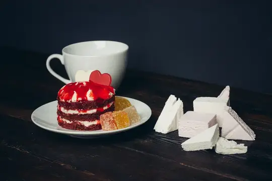 Красный торт с сердечком и белая чашка на тёмном столе