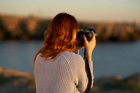 Женщина фотографирует море в горах, вид со спины