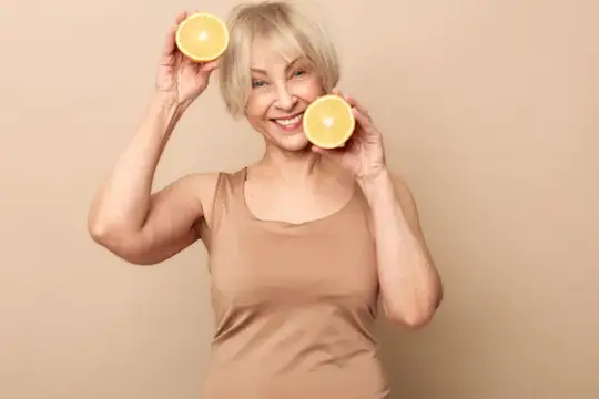 Улыбчивая седоволосая женщина с половинками лимона у лица