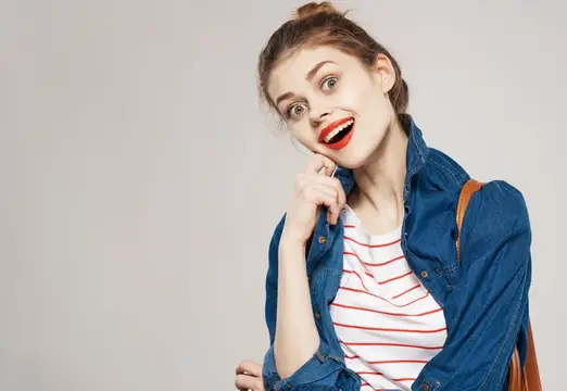 Красивая девушка с рюкзаком, одетая как модель или студентка, на сером фоне