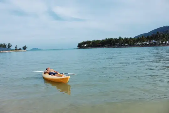 Мужчина лежит в жёлтой байдарке на спокойной морской воде