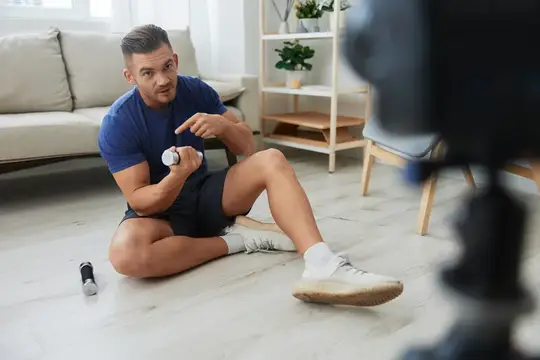 Спортивный мужчина записывает видео с гантелью на полу