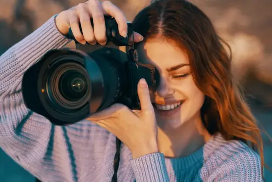 Улыбающаяся девушка с фотокамерой в руках на закате