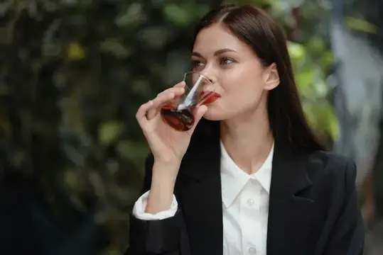 Молодая женщина в деловом костюме пьёт чай на природе